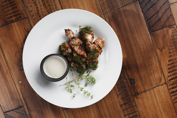Chicken wings barbecue in a white plate. Wooden background.