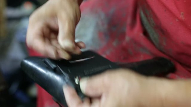 Calzolaio al Lavoro nella sua bottega artigianale. Chiodatura fondina nera per pistola. 