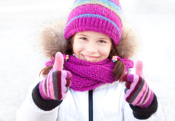 Child outdoors in winter clothes: hat, scarf and gloves