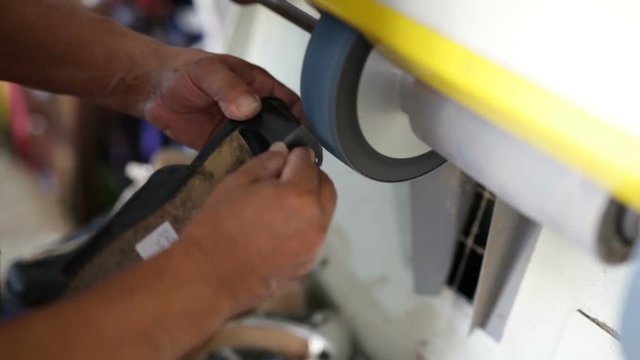 Calzolaio al Lavoro nella sua bottega artigianale. Smerigliatura bordo scarpa. 