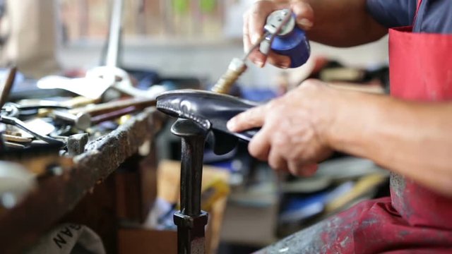 Calzolaio al Lavoro nella sua bottega artigianale. Incollatura suola scarpa nera uomo. 