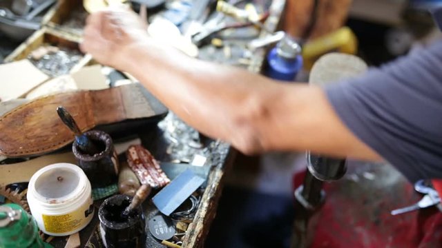 Calzolaio al Lavoro nella sua bottega artigianale. Inchiodatura con martello tacco scarpa nera da donna. 