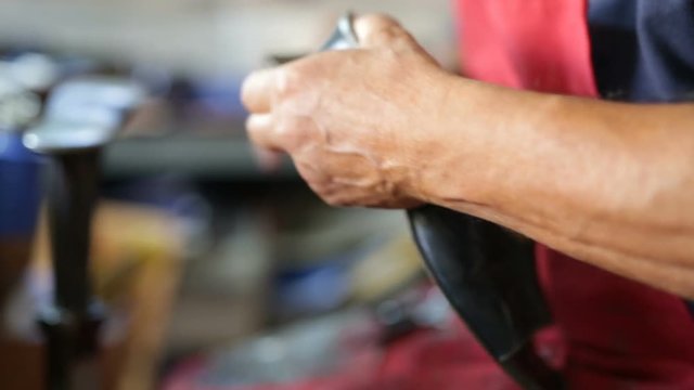 Calzolaio al Lavoro nella sua bottega artigianale. Ritaglio suola scarpa nera donna. 