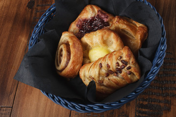 Sweet homemade buns in a blue basket. Wooden background.