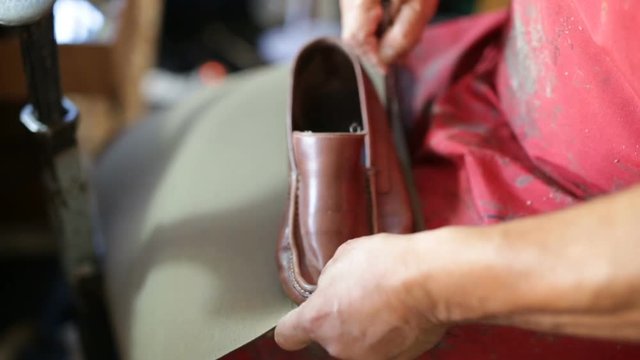Calzolaio al Lavoro nella sua bottega artigianale. Scontornatura per preparazione suola scarpa marrone Mocassino uomo. 