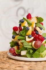 Delicious Christmas tree made of freash organic fruit and berries: raspberry, kiwi, apple, grapes, blueberry, strawberry, mint. Christmas dessert or snack for family celebrations. Season holidays.