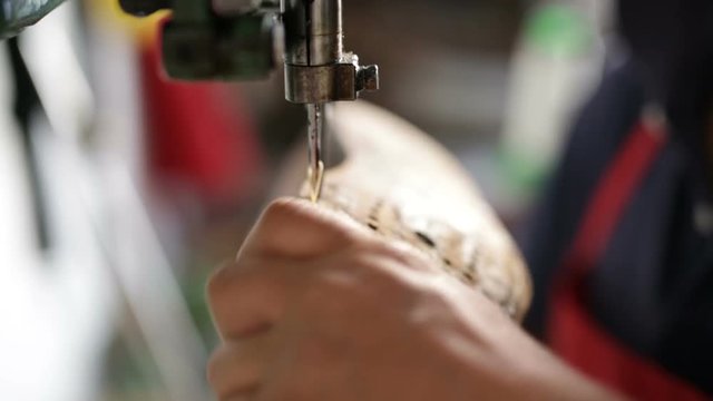 Calzolaio al Lavoro nella sua bottega artigianale. Cucitura a fili incrociati a macchina di una scarpa. 