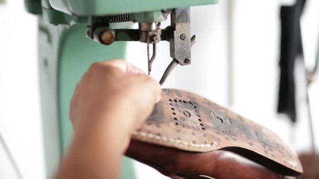 Calzolaio al Lavoro nella sua bottega artigianale. Cucitura suola scarpa da uomo. 