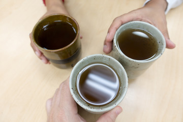 Three Multi-Ethnic People Toasting Ceramic Hot Brown Tea Mugs
