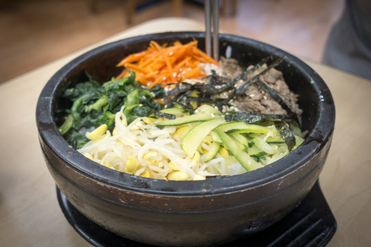 Dolsot Bibimbap Korean bowl, rice topped with beef and spinach, mushrooms, sea tangle, carrots, bean sprouts, and other seasoned vegetables
