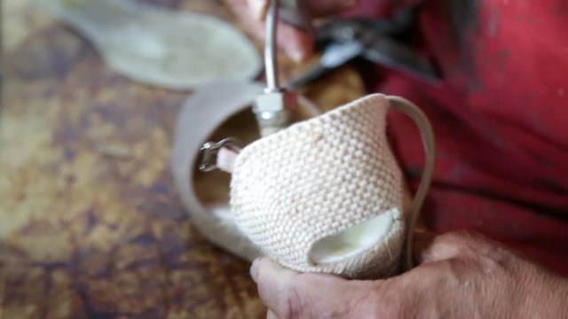 Calzolaio al Lavoro nella sua bottega artigianale. Incollatura interno zeppa bianca da donna. 