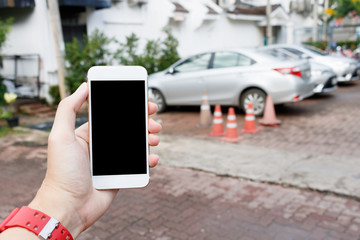 Man hand holding Smart phone showing blank screen with blur cars