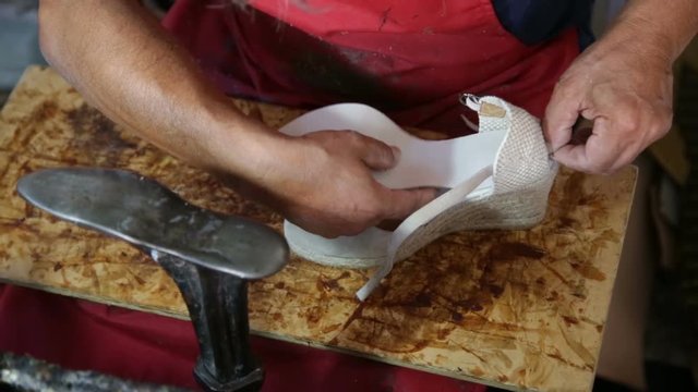 Calzolaio al Lavoro nella sua bottega artigianale. Incollatura suola interna scarpa zeppa da donna. 