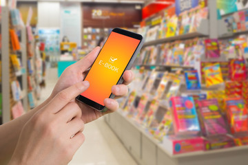 human hand hold and touch screen on smart phone with virtual app e-book over bookshelf