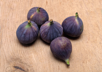 Still-life with five ripe figs fruits on brown wooden surface horizontal view closeup