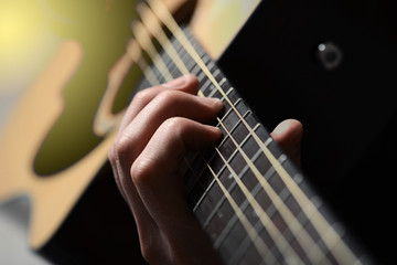 man's hands playing acoustic guitar