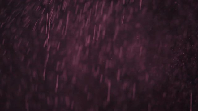 Reali particelle rosa di polvere in caduta libera con sfondo nero.