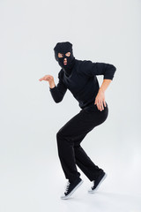 Funny scared criminal young man in balaclava running out