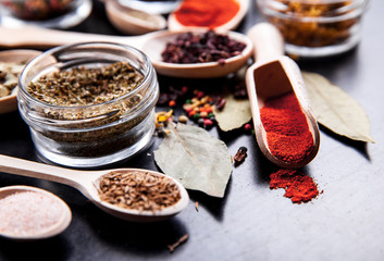 Spices on black background in special jars. Food