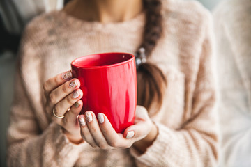 Woman's hand holding a red cup of coffee. With a beautiful winter manicure. Drink, fashion, morning