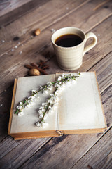 Large Cup of coffee on vintage wooden background. Spring flowers and books.