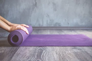 Selbstklebende Fototapete Yogaschule Frau rollt ihre Matte nach einer Yogastunde