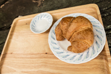 Croissant baked on wooden plate with copy space.