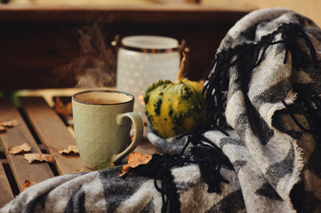 cozy autumn morning at country house, cup of tea and warm blanket on wooden table. Still life details