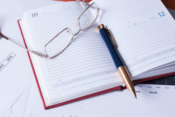 The business concept. Notebook, pen and glasses on top of financial charts