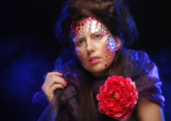 young woman with artistic visage holding big red flower