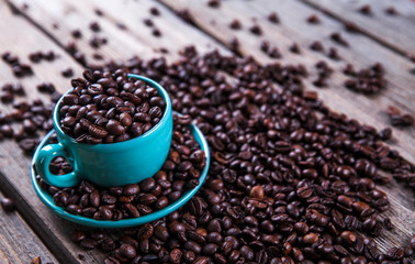 Turquoise cup with coffee beans on a wooden background. Beverage, tableware
