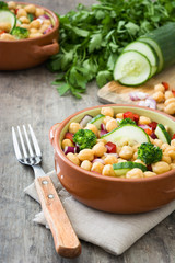 Chickpea salad in brown bowl on wooden background

