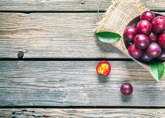 Old plate with plums over dark board. Top view. Fruits background with space for text. Agriculture, Gardening, Harvest Concept.