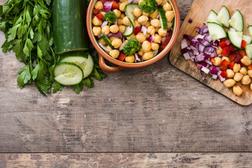 Chickpea salad in brown bowl on wooden background

