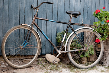 Fototapeta na wymiar Old bicycle near a blue wooden fence in village