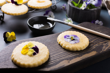 Process of making shortbread cookies with edible flowers on old wooden background. Holiday food