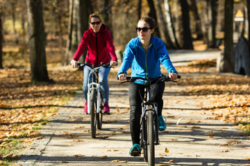 Two women riding bicycles in city 