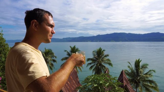 Male traveler drinking coffee and looking at Toba lake from Samosir island