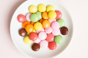Colorful chocolate buttons on pink background 