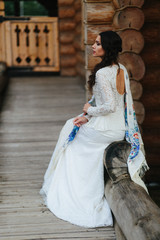 Daydreaming lady in a white dress sits in a shawl on the wooden