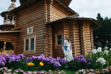 Straight lady in a long white dress stands behind old wooden chu