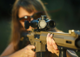 Girl with a gun for trap shooting and shooting glasses aiming at