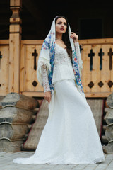White shawl with blue flowers covers bride's head