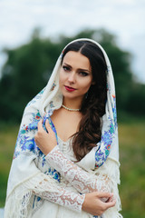 Shawl covers a delicate brunette posing on the green field