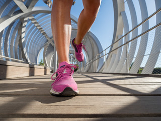 Running shoes closeup of a female runner on a modern bridge. - 121125605