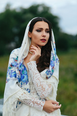 Sad stunning brunette  poses on the field in white shawl with bl
