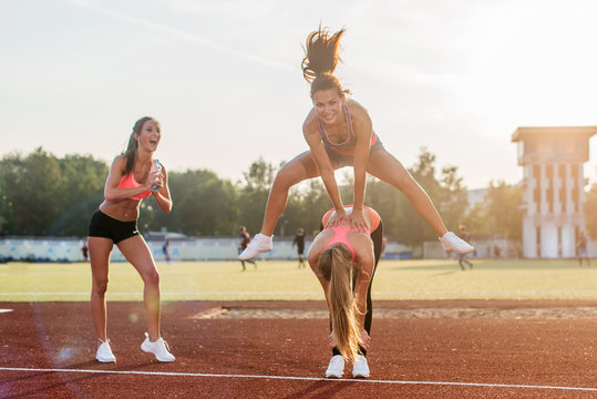 Fit Women At The Stadium Playing Leap Frog.