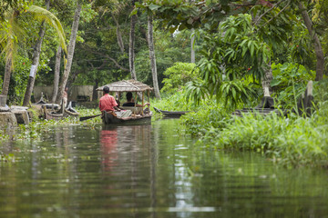 Unidentified indian people in small boat in Kerala backwaters.