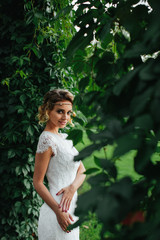Woman in a lace white dress looks mysterious posing in a green p