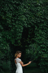 Naklejka premium Delicate woman touches green tree branch standing in a garden